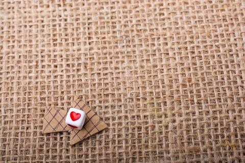 Love cubes on arrow cut out of brown paper on canvas