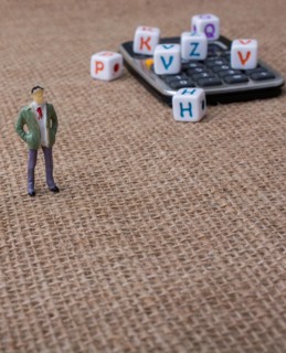 Colorful letter cubes and a calculator beside a figurine