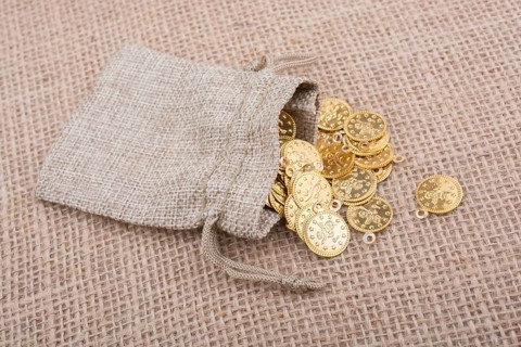 Fake gold coins out of a little sack on canvas