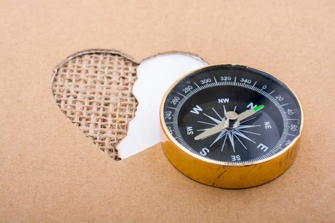 Heart shaped gold color metal object in hand