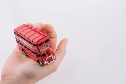 Hand holding a London double decker bus on a white background