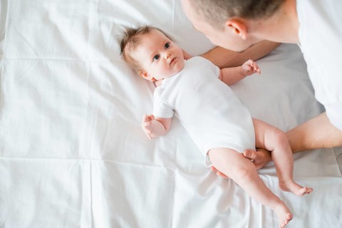 Father softly embracing baby bed