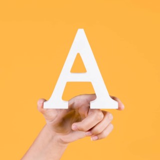 Human hand holding up uppercase capital letter yellow background