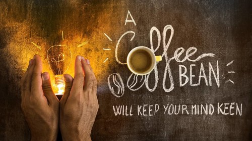 Hand covering illuminated light bulb with text chalkboard