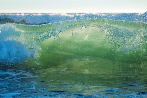 Breaking ocean wave on sunset backlit with sun. Fonte da Telha