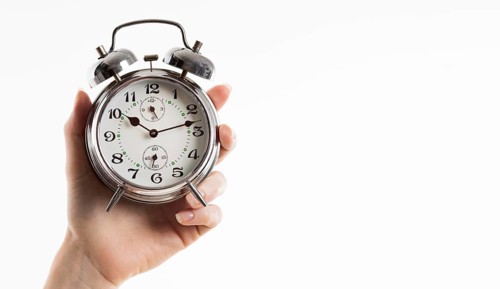 Hand holding alarm clock with copy space