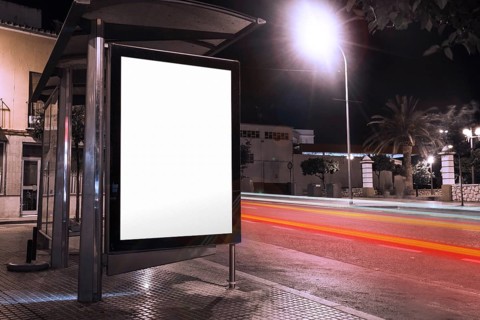 Blank advertisement bus shelter with blurred traffic lights night