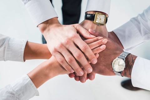 People putting stacked hands together promising help support against white backdrop