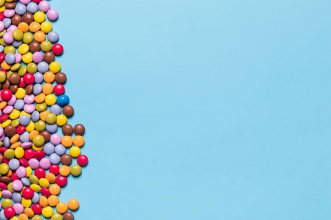 Colorful gem candies side blue background