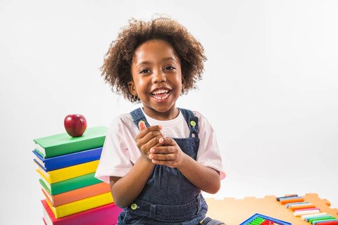 Kid sitting books smiling studio