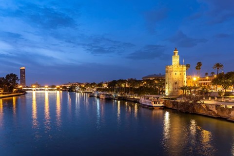 On the banks of the Guadalquivir River with the historic Torre del Oro tower at dusk