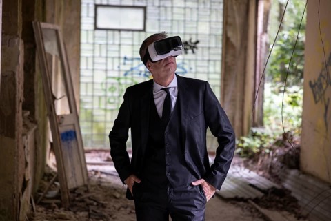 Man dressed in suit wearing VR glasses in a dilapidated office building