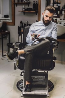 Customer watching magazine barbershop