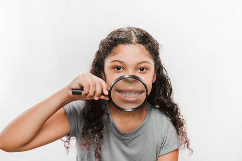 Close up girl with magnifying glass showing her teeth