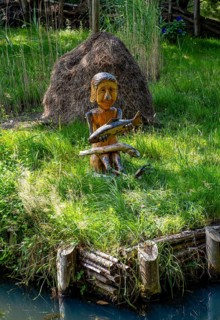 Wooden figure with fish in hands on the bank of the Spree