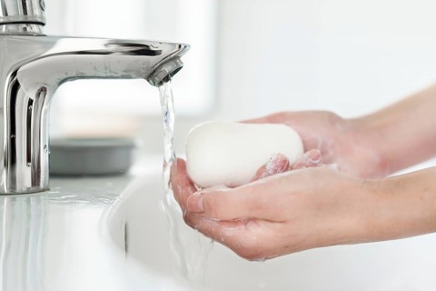 Side view hands washing bar soap sink
