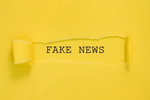 Torn fake news paper yellow wall