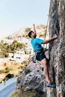 Side view sporty man climbing rock