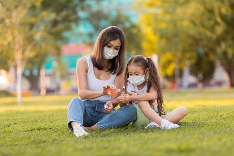 Asian mother daughter using disinfectant outside