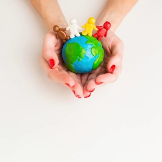 Top view hands holding globe with people figurines