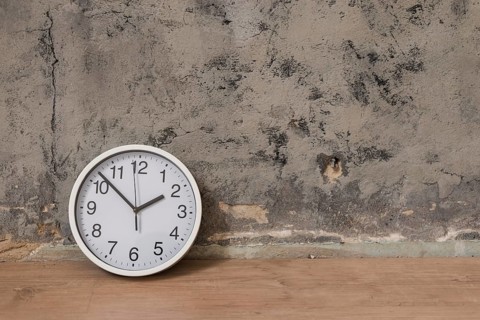Clock wooden desk against weathered wall