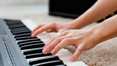 Close up female musician playing piano keyboard