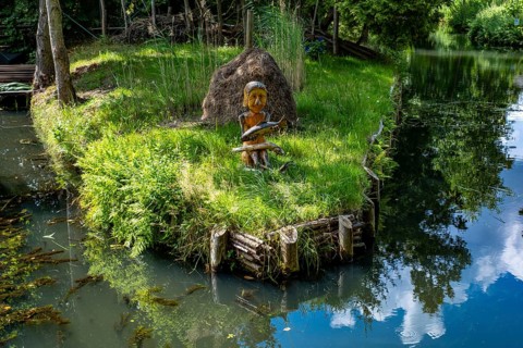 Wooden figure with fish in hands on the bank of the Spree