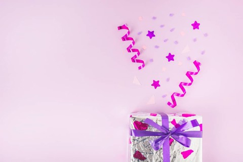 Curled streamers star shape confetti silver gift box against pink background