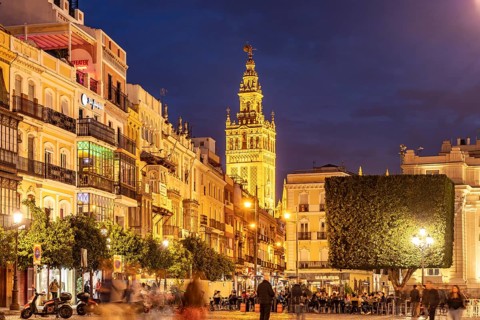 Restaurants in the Plaza de San Francisco and the Giralda bell tower of Santa Maria de la Sede Cathedral at dusk