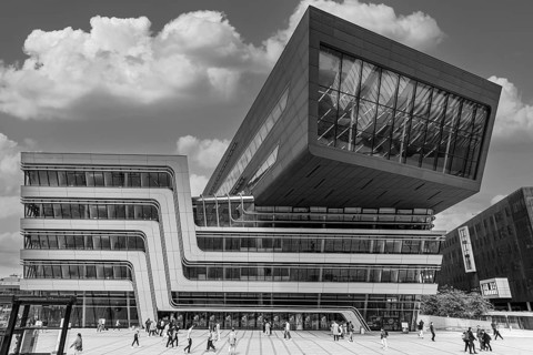 Students in front of a modern building on the campus of the University of Economics WU