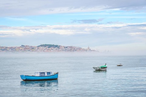 Fishing boats in Tagus river on misty morning with Lisbon in background with miSt Lisbon