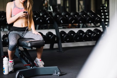 Girl with phone sitting gym