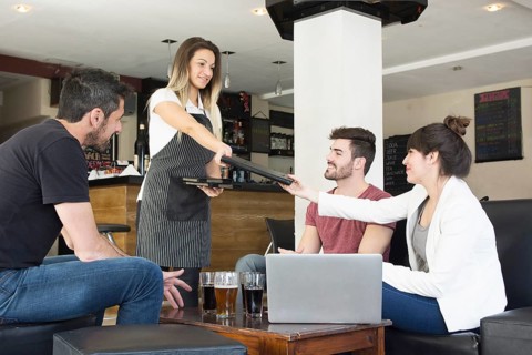 Waitress presenting menu female customer with friends bar