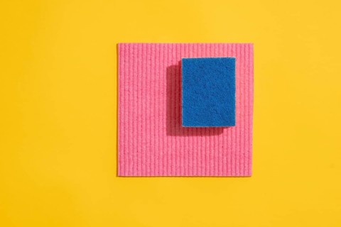 Dishcloth and dishwashing sponge on yellow background