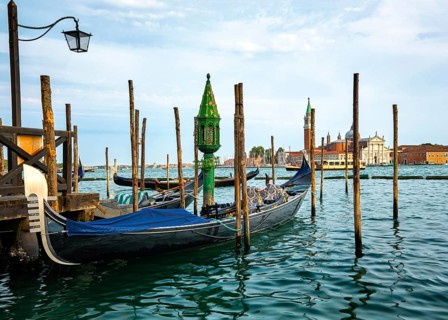 Beautiful view of traditional Venetian gondola moored by jetty and floating on waters of Grand Canal in Venice