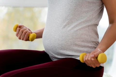 Pregnant woman using yellow weights