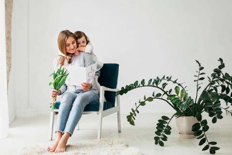 Daughter hugging mother with greeting card