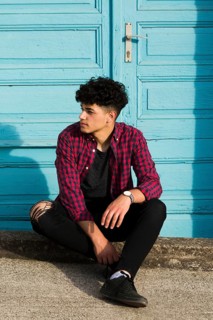 Sitting ethnic teenager checkered shirt curb