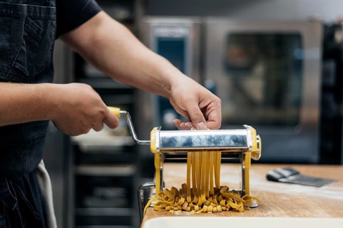 Male chef using machine chop fresh pasta dough