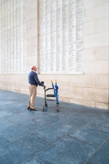 A senior citizen with a walker stands in the Men's Gate