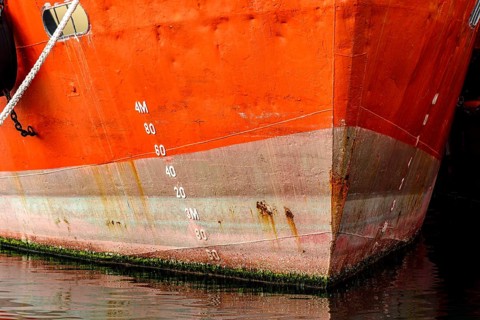 Old ship bow showing signs of deterioration with rust and parasites attached to the hull