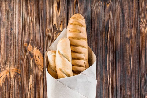 Baguettes wrapped paper wooden background