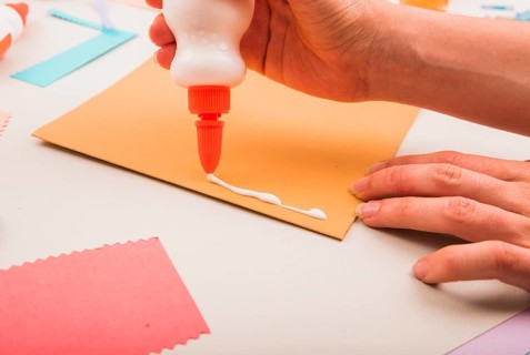 Close up person s hand applying white glue paper