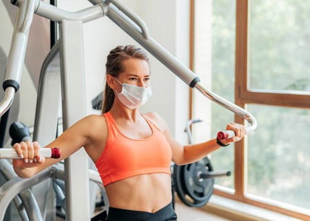 Woman gym doing exercises with medical mask