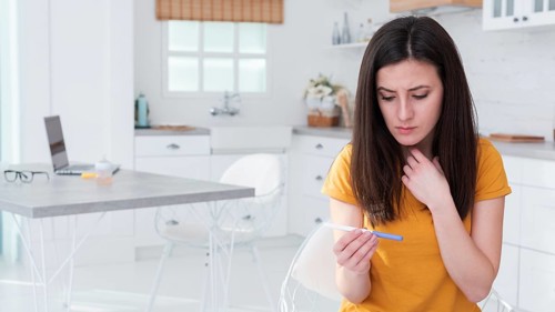 Worried woman holding pregnancy test