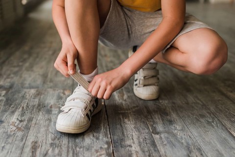Low section boy putting shoe strap hardwood floor