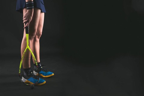 Player holding racket her legs