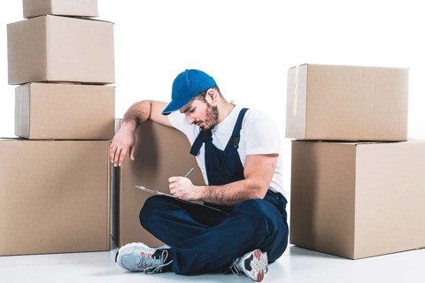 Courier writing clipboard near parcels