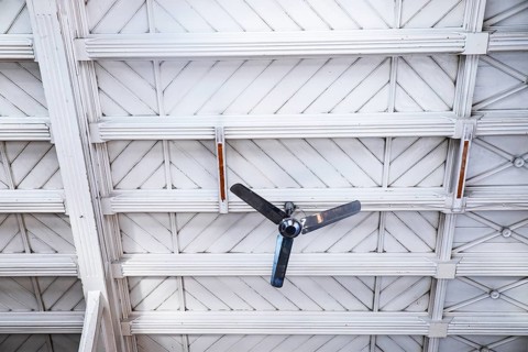 Fan in front of a white wooden ceiling