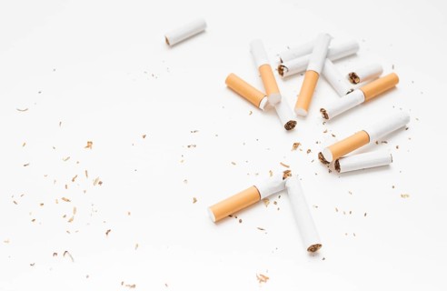 Overhead view broken cigarette tobacco against white backdrop
